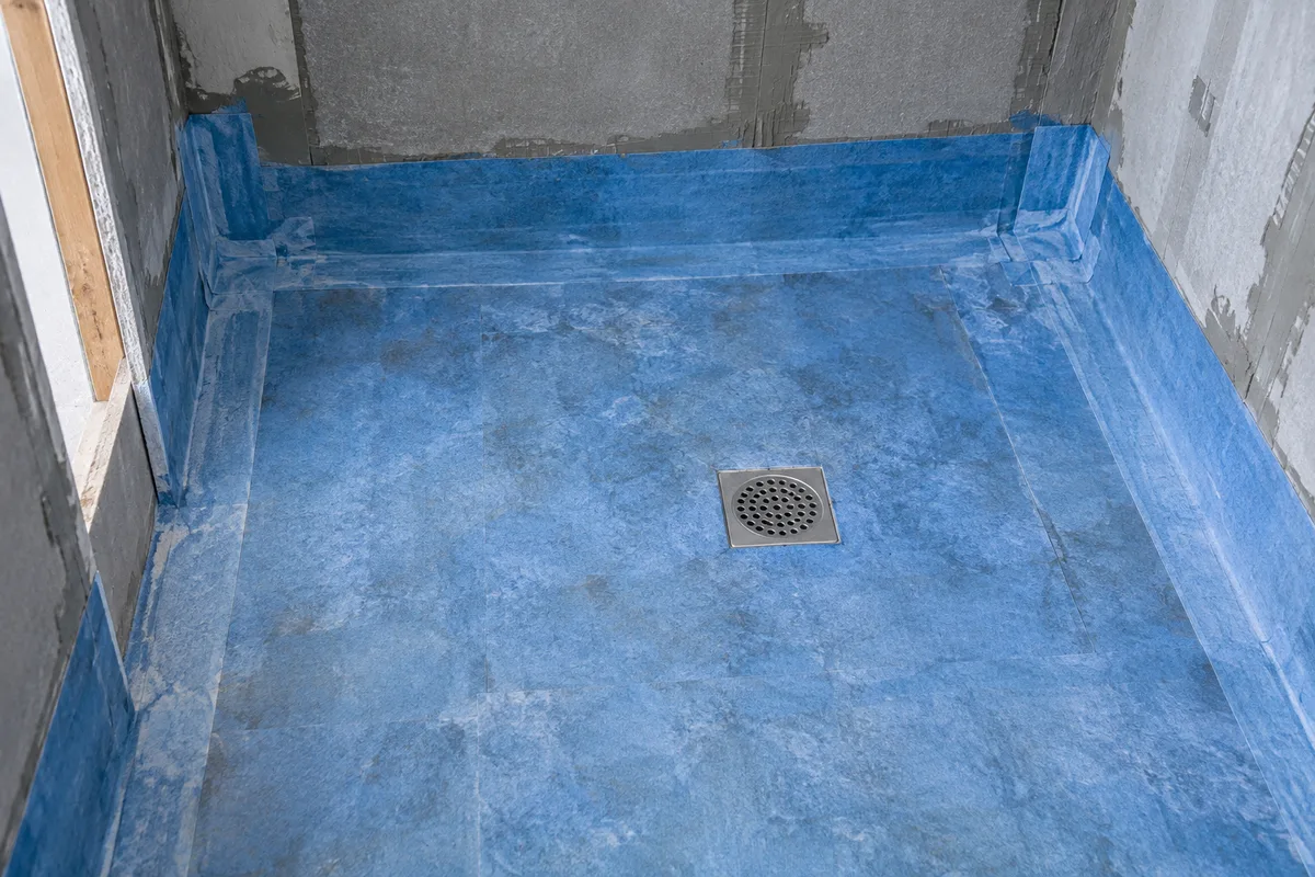 Douche à l&rsquo;italienne en cours de réalisation avec membrane d&rsquo;étanchéité remontant le long des murs