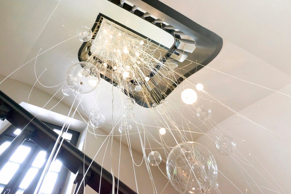 Staircase with glass bubble chandelier and black painted wooden balustrade