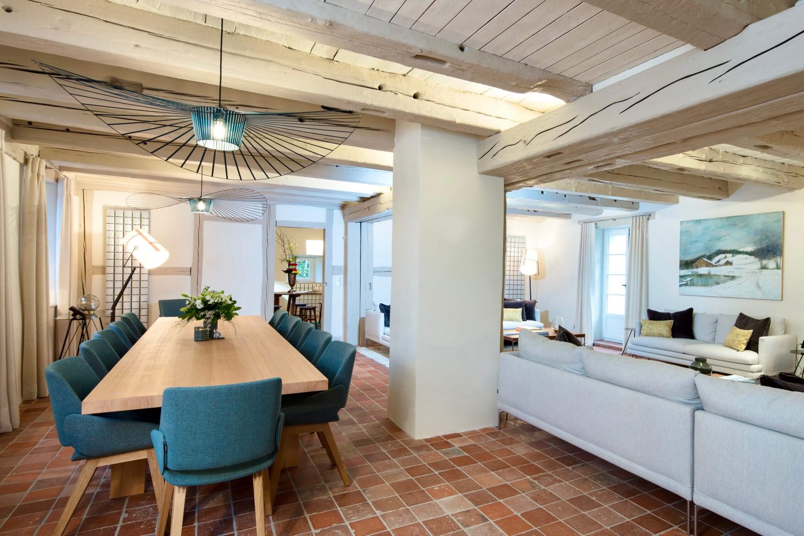 Vue d’ensemble d’un salon et d’une salle à manger rénovés par Charles-Eric Guerrier, architecte d’intérieur à Paris, avec poutres apparentes, sol en terre cuite et mobilier contemporain.