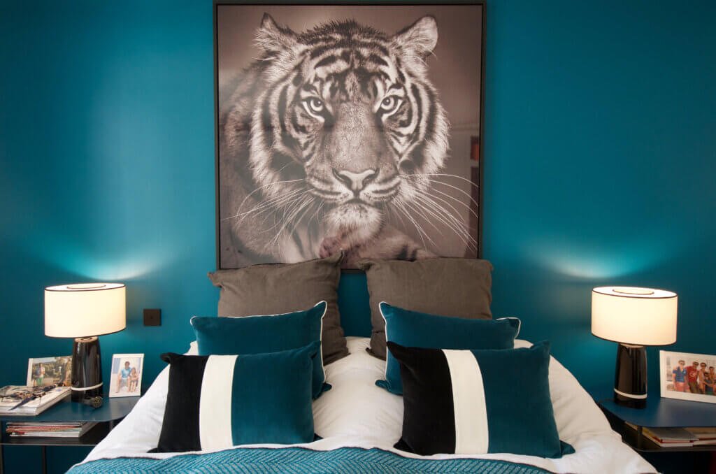 Paris residential bedroom with teal walls, bespoke lighting, and large tiger artwork above the bed