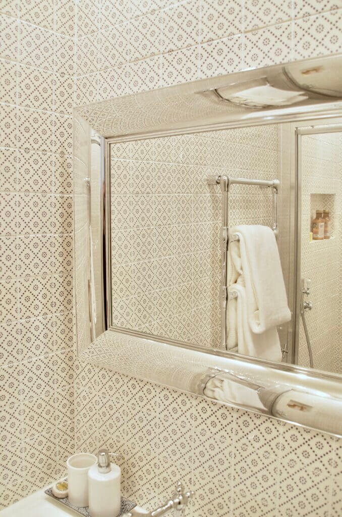Bathroom detail with patterned wall tiles and framed mirror by Philippe Starck