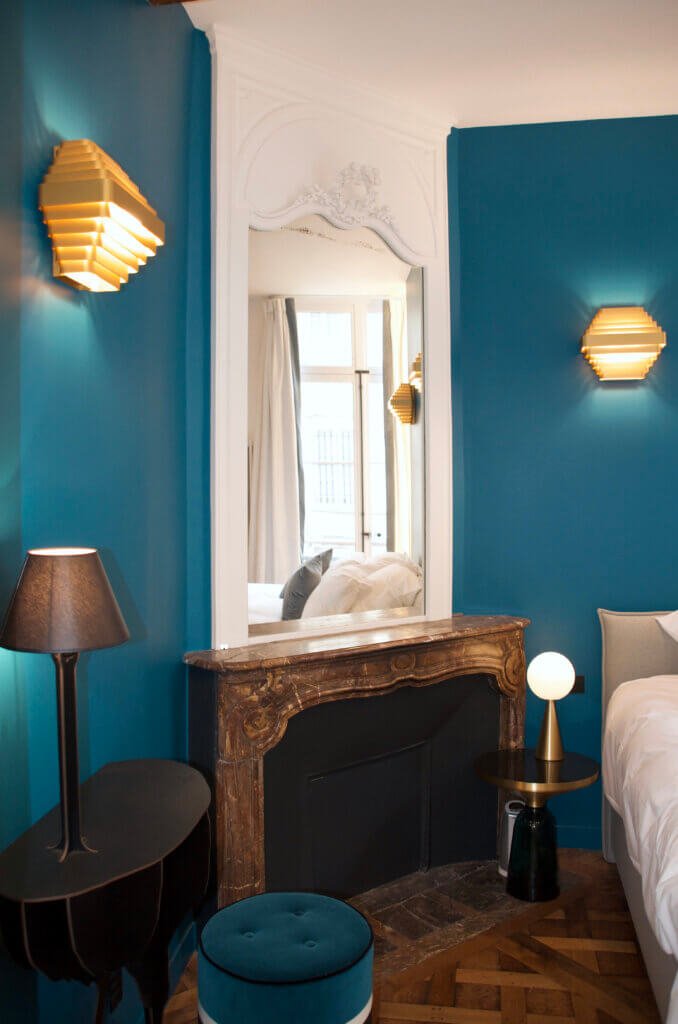 Bedroom view with restored fireplace, framed mirror and wall-mounted lighting