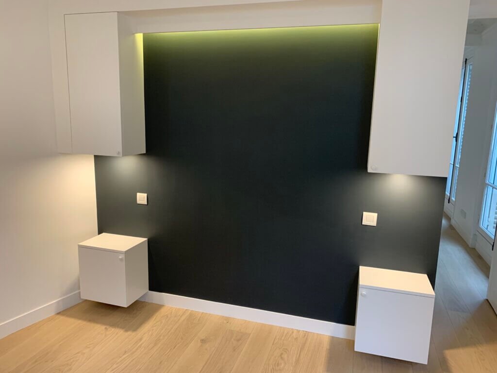 Custom headboard wall with integrated storage and indirect lighting in a Paris apartment bedroom