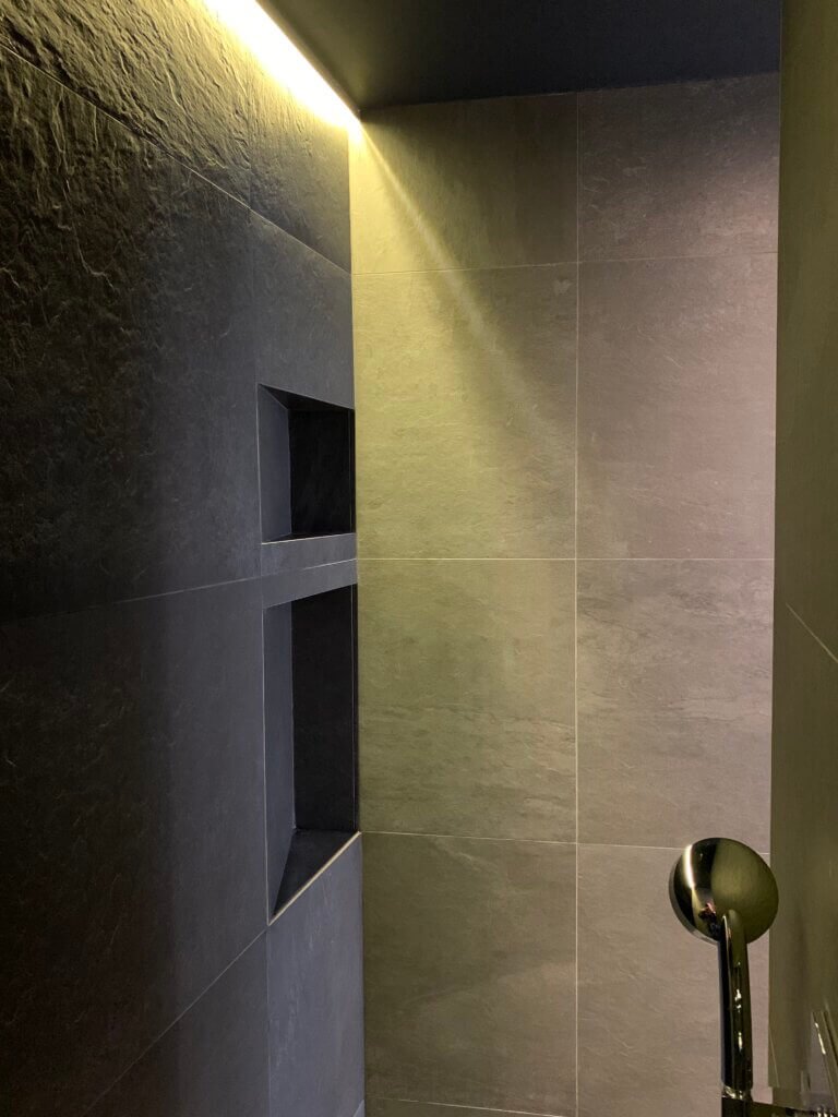 Walk-in shower with recessed wall niches and indirect lighting in a Paris apartment bathroom