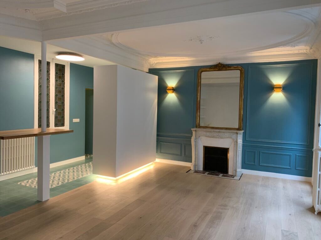 Renovated Parisian living space featuring restored moldings, fireplace, integrated lighting and open-plan layout