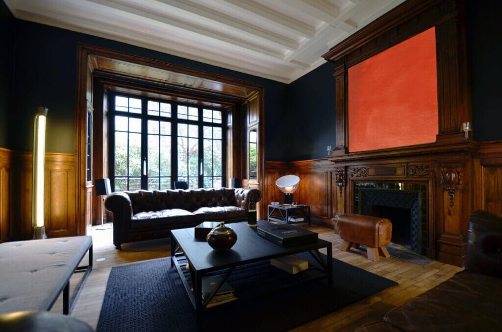 Main reception living room with preserved wood paneling and contemporary furnishings in a Paris private townhouse