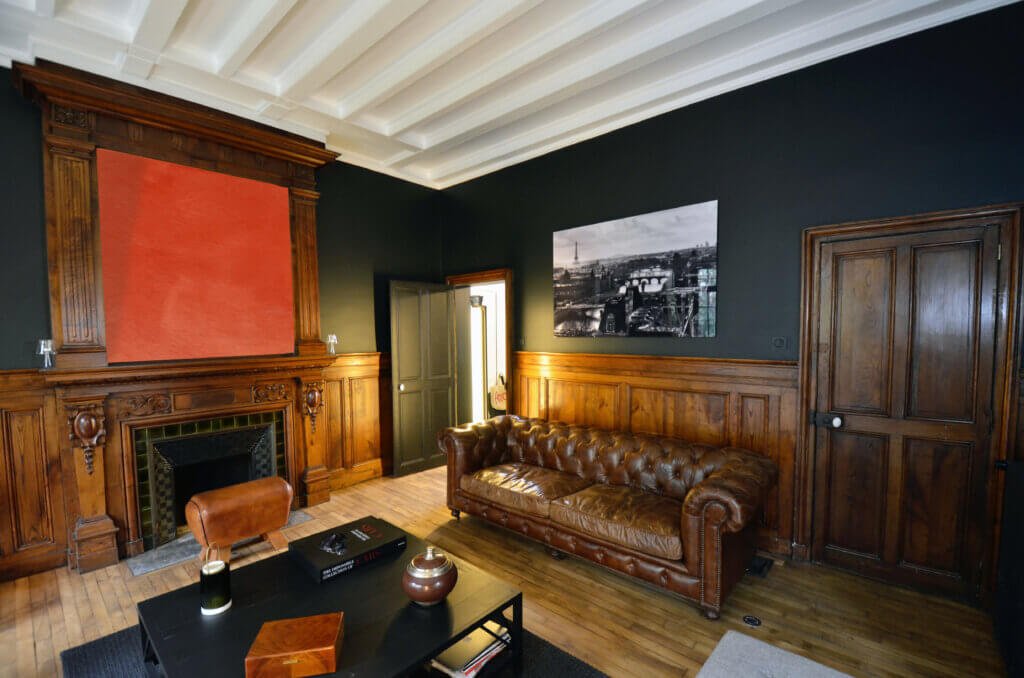 Main reception living room with restored wood paneling and coordinated lighting in a Paris townhouse